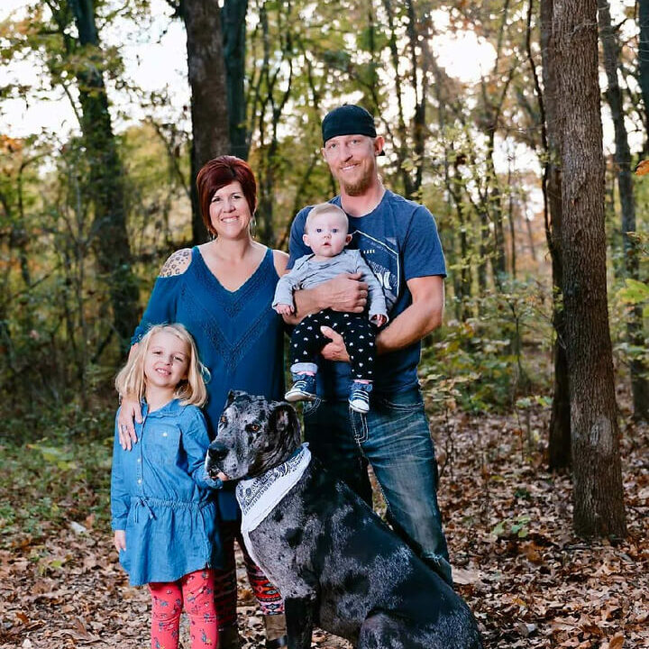 A family posing for a picture with their dog.